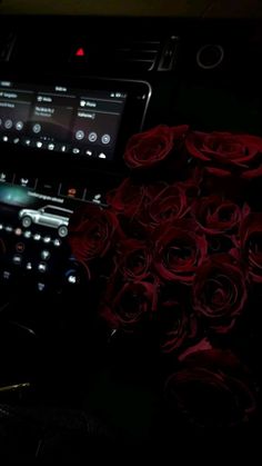 a bunch of red roses sitting next to a keyboard in the dark with lights on