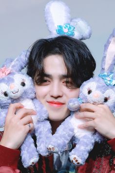 a person holding three stuffed animals in front of their face and smiling at the camera