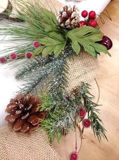 pine cones, berries and greenery sit on a burlocked tablecloth