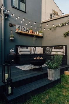 an outdoor living area with couches, potted plants and string lights