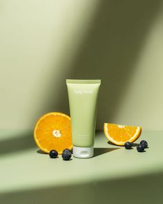 an orange slice next to a tube of body lotion and some blueberries on a table