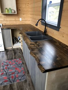 a kitchen counter made out of wood with a sink and window in the back ground