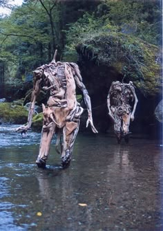 two sculptures made out of tree trunks in the middle of a river with water running through them