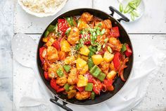 a skillet filled with chicken and vegetables on top of a white cloth next to a fork