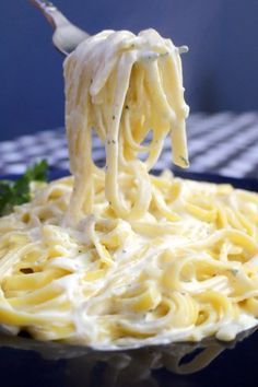 a fork full of noodles being lifted from the plate