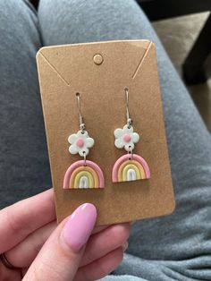 a pair of pink and yellow earrings with flowers on them in front of a card