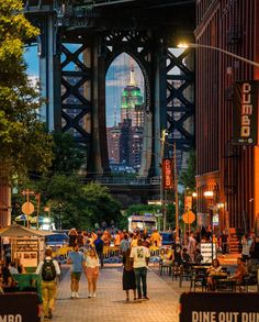 people are walking on the sidewalk under an overpass in new york city at night