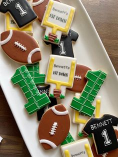 decorated cookies on a plate with footballs and jersey designs for sports fans to decorate