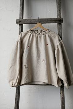 Tokyo tunic is made from 100% soft and washed linen.  Details: - Colour: Sand - Composition: 100% Oeko-Tex certified linen - Embroidery - hedgehog, pine tree, autumn leaves, mushroom, berries, acorn - from both sides (front and back) - Ruffle neckline - Dropped shoulders - Long sleeves - Loose fit - Medium weight linen - Linen care: machine wash gentle; tumble dry low, ironing optional - The price is for one tunic, other pictured items are not included Folk Style Long Sleeve Linen Tops, Embroidered Linen Long Sleeve Blouse, Peasant Style Beige Linen Top, Folk Style Linen Top With Floral Embroidery, Embroidered Linen Tops With Relaxed Fit, Folk Style Embroidered Linen Top, Embroidered Linen Folk Tops, Relaxed Fit Linen Blouse With Floral Embroidery, Peasant Long Sleeve Linen Tops