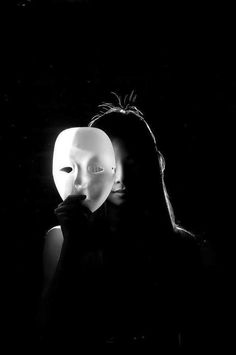 a woman holding a mask in front of her face with the light shining through it