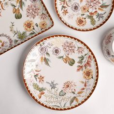 three plates with flowers painted on them next to a vase