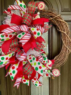 a wreath with candy canes and bows hanging on the front door for holiday decor