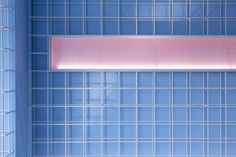 a blue tiled wall with a pink light above it