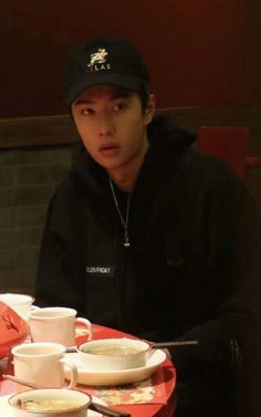 a man sitting at a table with plates and cups on it, in front of him