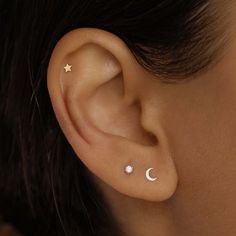 a woman's ear with two stars and a crescent piercing