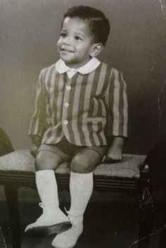 an old photo of a young boy sitting on a bench