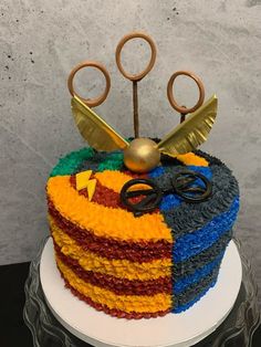 a multicolored cake with scissors and other items on top, sitting on a plate