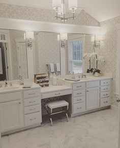 a large bathroom with double sinks and mirrors on the wall, along with white cabinetry