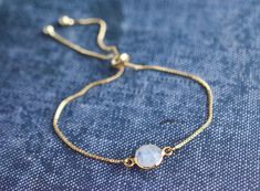 This minimalist style moonstone bracelet is perfect for everyday wear. It's beautiful on its own, but also makes a great layering piece. Created with a gold electroplated rainbow moonstone connector that is attached to a dainty gold plated chain with a slider bead that makes it adjustable. It is finished off with two gold ball ends. Each piece is one of a kind so your stone may look slightly different than the one featured in the photos. All of my bracelets come packaged in a kraft cotton filled Dainty Moonstone Bracelets For Everyday, Gold Moonstone Round Bracelets, Adjustable Gold Moonstone Bracelet, Gold Moonstone Bracelet With Gemstones, Gold Moonstone Gemstone Bracelets, Elegant Moonstone Bracelets, Elegant Everyday Moonstone Bracelets, Dainty Round Moonstone Bracelets, Delicate Gold Moonstone Bracelet