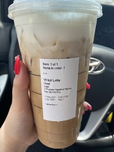 a woman holding up a cup of iced coffee in her hand with information on it