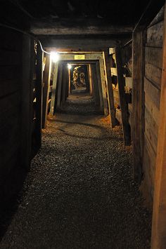 a long narrow tunnel with light at the end and gravel flooring on both sides