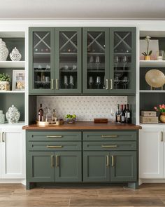 a kitchen with green cabinets and gold handles on the countertop, along with white cupboards