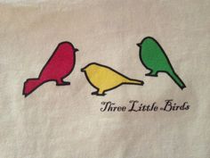 three little birds on a white towel with the words thru little birds written in red, yellow and green