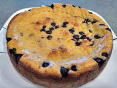 a cake with blueberries on top is sitting on a white plate, ready to be eaten