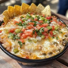 a close up of a bowl of food with chips on the side and salsa in the middle