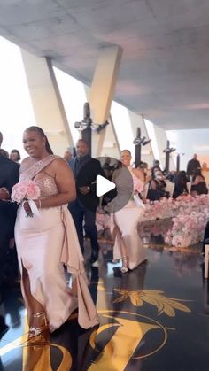 a woman in a pink dress is walking down the aisle with other people behind her