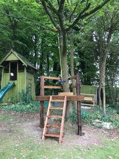 a tree house with a slide in the middle of it and some trees around it