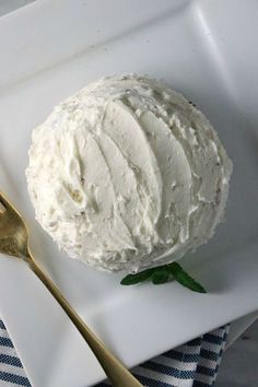 a white plate topped with whipped cream next to a gold fork and spoon on top of a blue and white table cloth