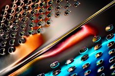 several different colored metal objects with holes in them and some water droplets on the surface