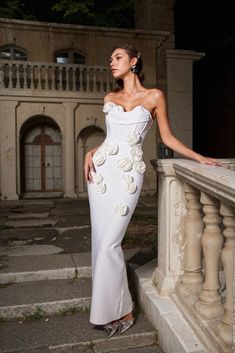 a woman in a white dress standing on some steps