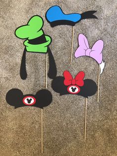 four mickey mouse head cupcake toppers on a stick with eyes, ears and bows