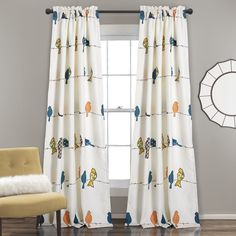 the curtains in this room are decorated with birds and trees on white fabric, along with a yellow chair