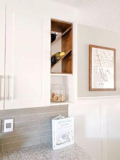 a kitchen with white cabinets and marble counter tops in front of a map on the wall