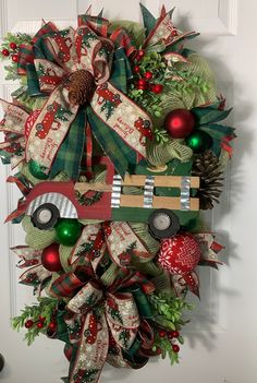 a christmas wreath is hanging on the front door with ornaments around it and an old truck