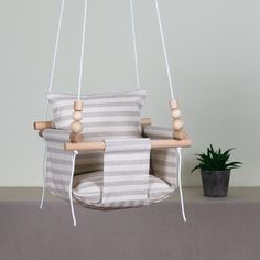 a white and grey striped chair hanging from a wooden frame with two pillows on it