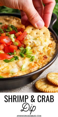 a person dipping some food into a skillet with crackers on the side and green onions