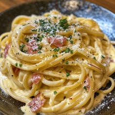 a plate of pasta with ham and parmesan cheese on the top is ready to be eaten