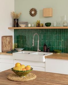 a bowl of fruit sitting on top of a wooden table next to a kitchen sink