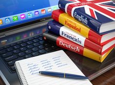 a stack of books sitting on top of a laptop computer next to a pile of notebooks