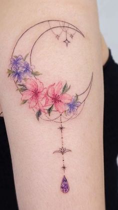 a woman's thigh with flowers and a crescent tattoo