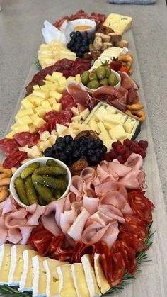 an assortment of cheeses, meats and vegetables on a platter with olives