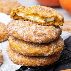 a stack of sugared donuts sitting on top of a cooling rack next to oranges