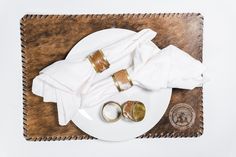 two wedding rings and napkins on a white plate with brown cow hide placemat