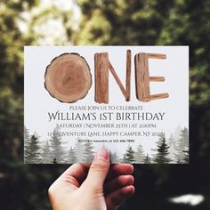 someone is holding up a birthday card with the word one on it in front of some trees