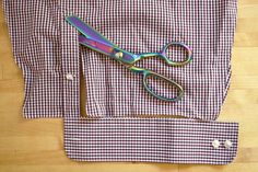 a pair of scissors sitting on top of a checkered shirt