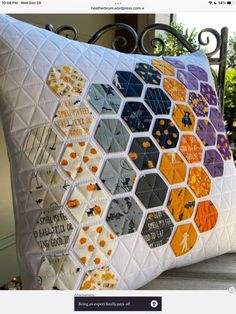 a pillow made out of hexagons on top of a wooden bench in front of a house